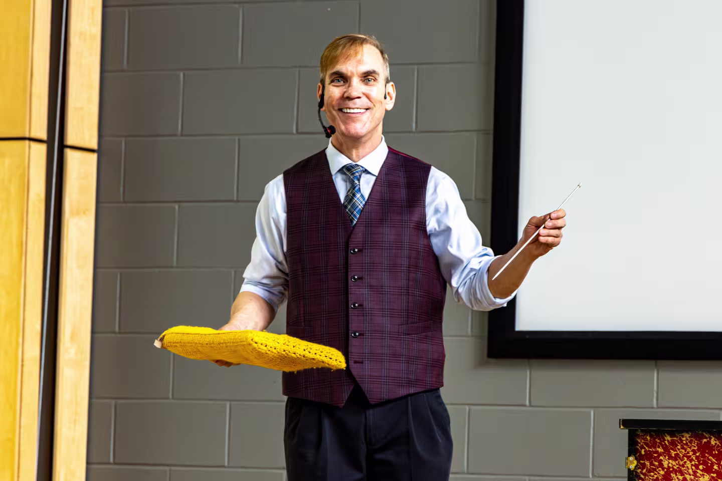 Photo de René Lacourcière, magicien qui tient une enveloppe jaune dans sa main droite et une baguette magique dans sa main gauche.