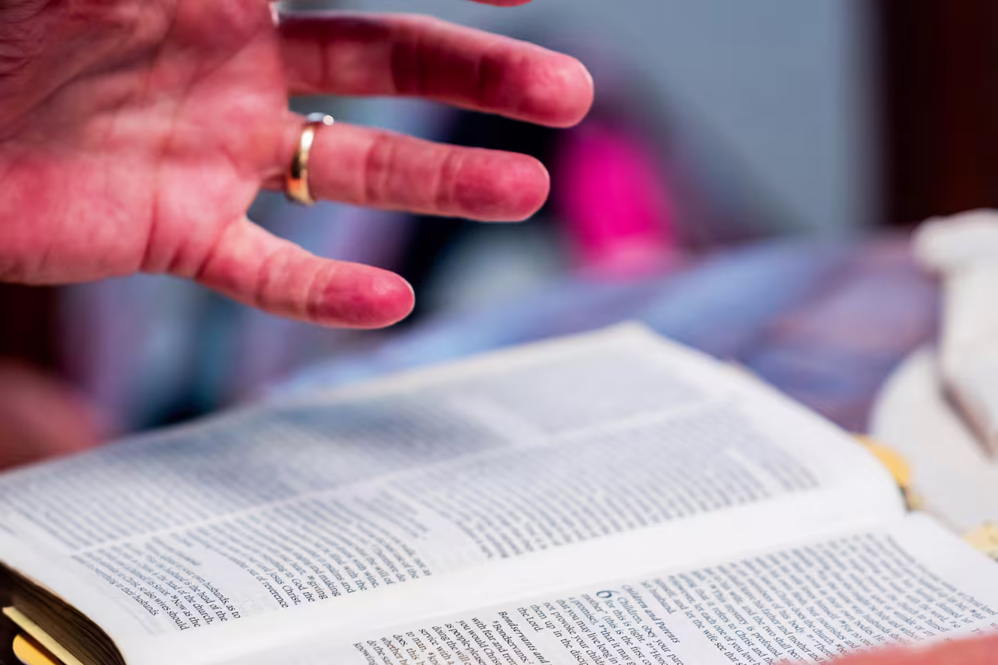 Photo d'un livre ouvert avec des mains, dont une est surélevée et démontre que la personne discute du livre.