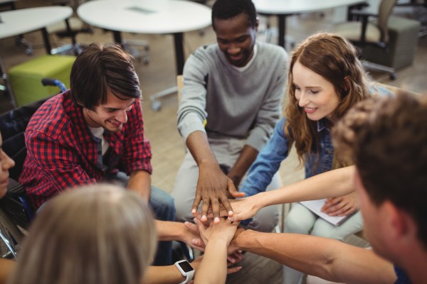 Un groupe de personnes faisant une activité d'équipe, les mains étendues vers le centre.