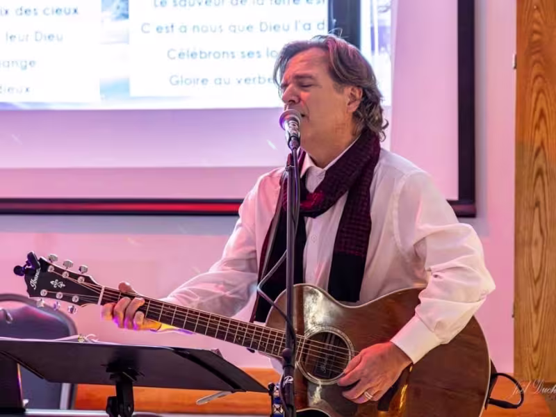 Photo de Éric Romanic, guitare au cou, chantant dans un micro.