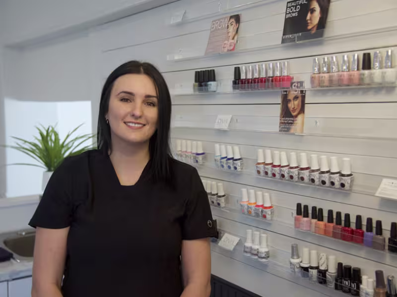 Portrait de Sophie Laforge devant le présentoire de produits de sa boutique.