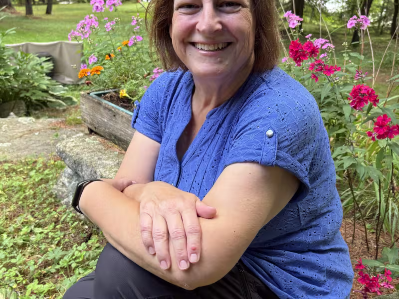 Photo de Joanne Héroux Farrow, assis devant un bac à fleurs rouges