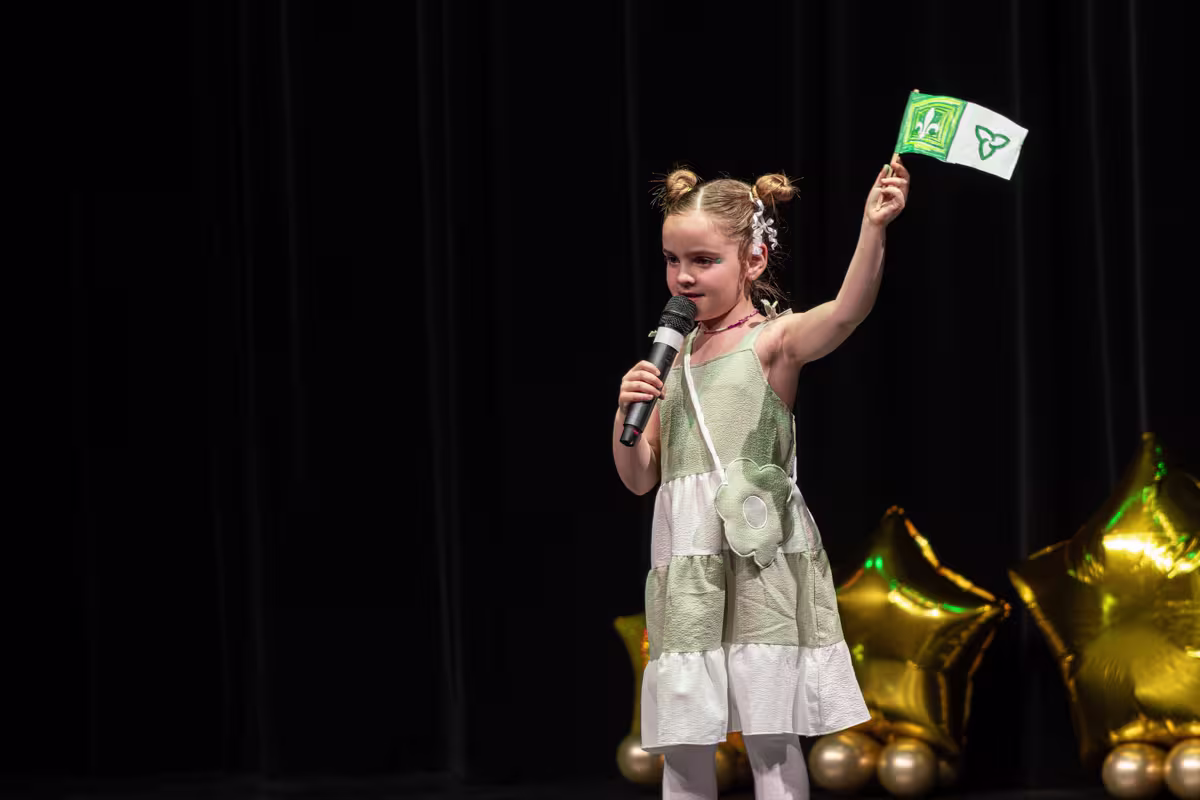 Jeune fille qui chante tenant un petit drapeau franco-ontarien