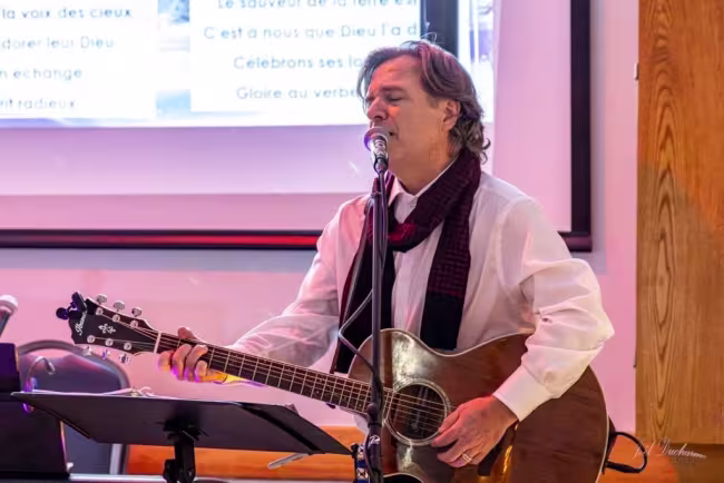 Photo de Éric Romanic, guitare au cou, chantant dans un micro.