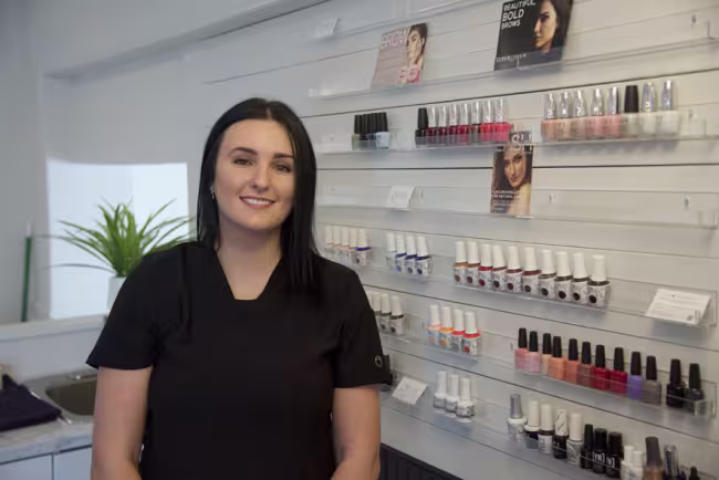 Portrait de Sophie Laforge devant le présentoire de produits de sa boutique.