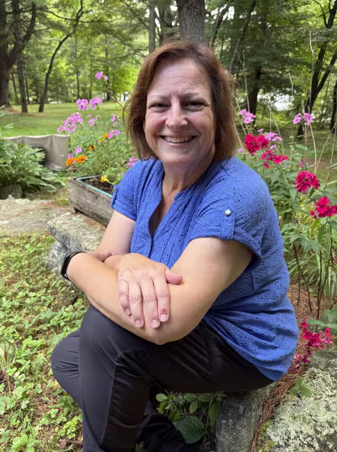 Photo de Joanne Héroux Farrow, assis devant un bac à fleurs rouges
